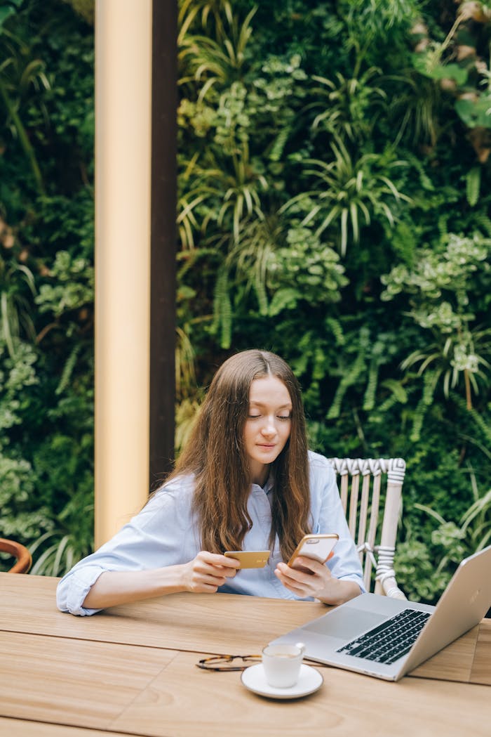 Young woman using smartphone and credit card for online shopping outdoors.